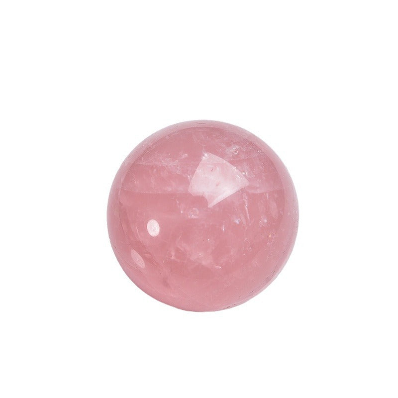 The contrast between the raw rose crystal stone and the polished sphere highlights the craftsmanship
