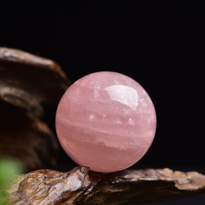 The surface of the rose quartz ball is smooth and polished, with details showcasing the natural texture