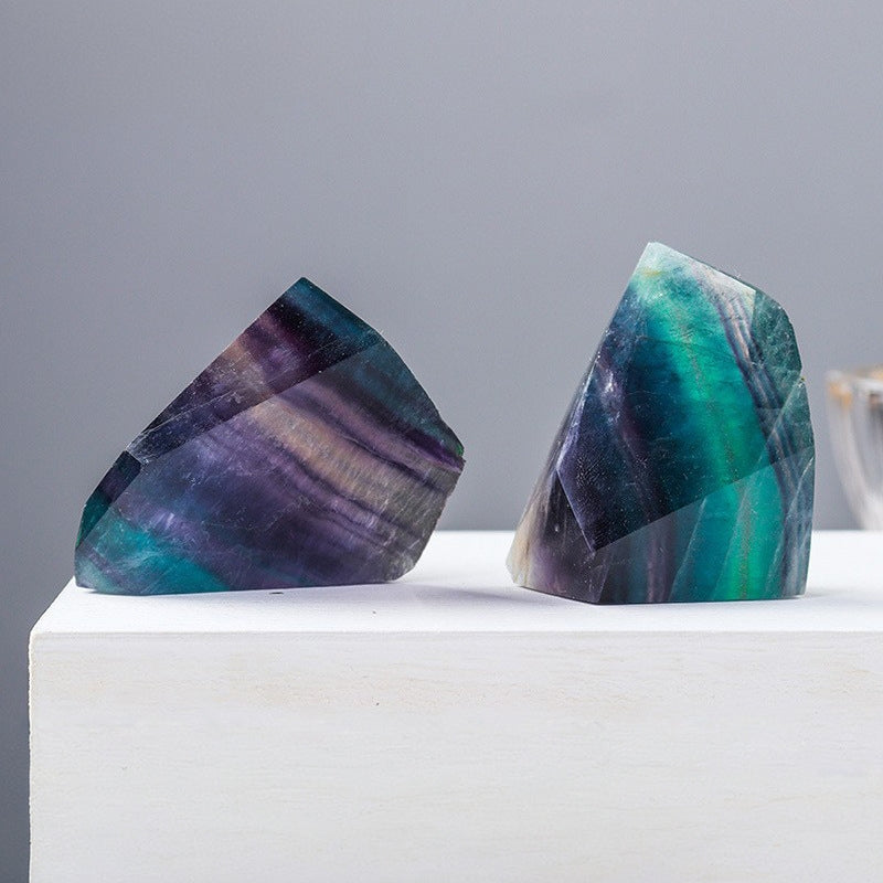 The green and purple fluorite geometric shape is placed beside the laptop as an energy guardian stone for creative workers, helping to neutralize electromagnetic waves and stimulate innovative thinking.