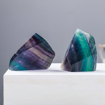 The green and purple fluorite geometric shape is placed beside the laptop as an energy guardian stone for creative workers, helping to neutralize electromagnetic waves and stimulate innovative thinking.