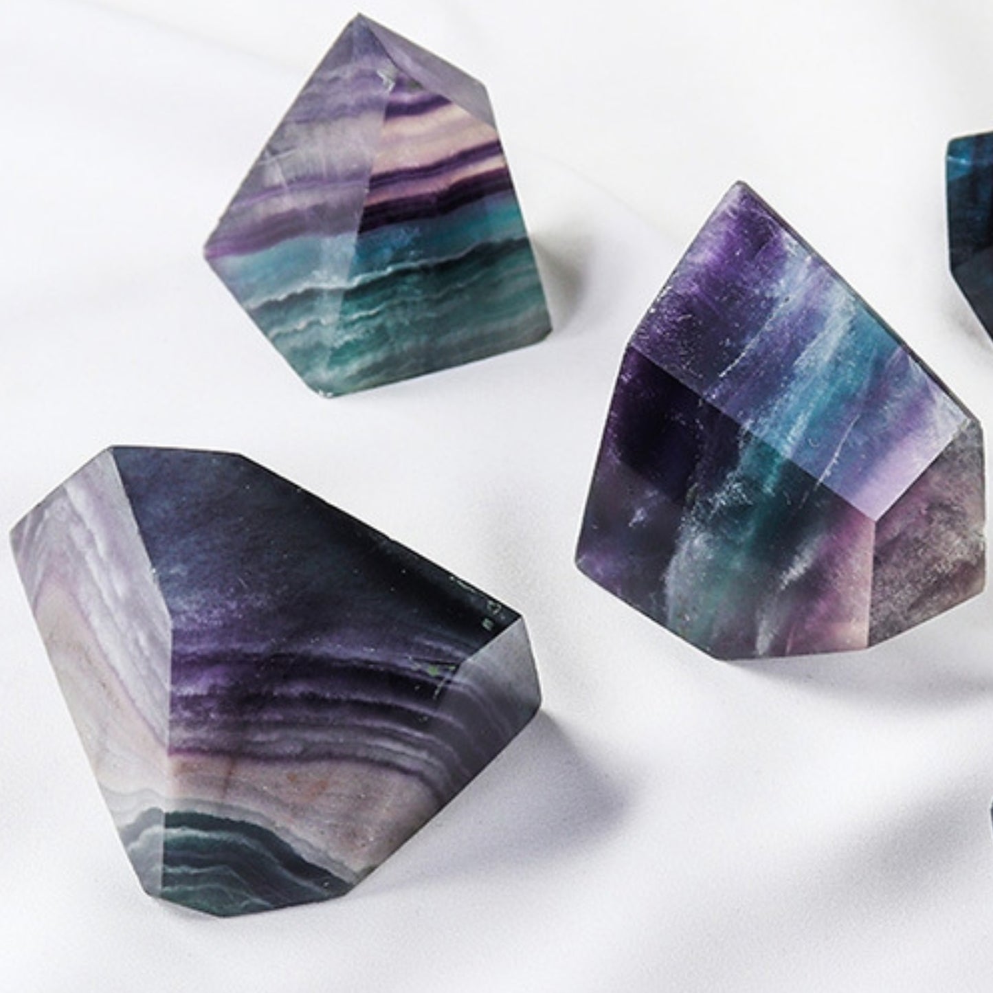 The complete set of the "Crystal Box" seven-color fluorite Energy Geometry Set is on display, featuring various geometric forms such as green fluorite cones and purple fluorite spheres, showcasing their richness as energy combinations.