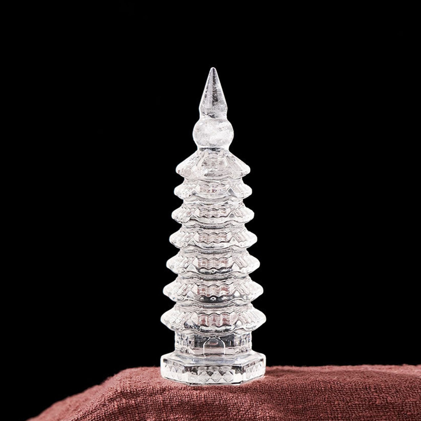 A close-up of a natural white crystal success energy tower on a modern desk, with a laptop and a leather notebook placed beside it.