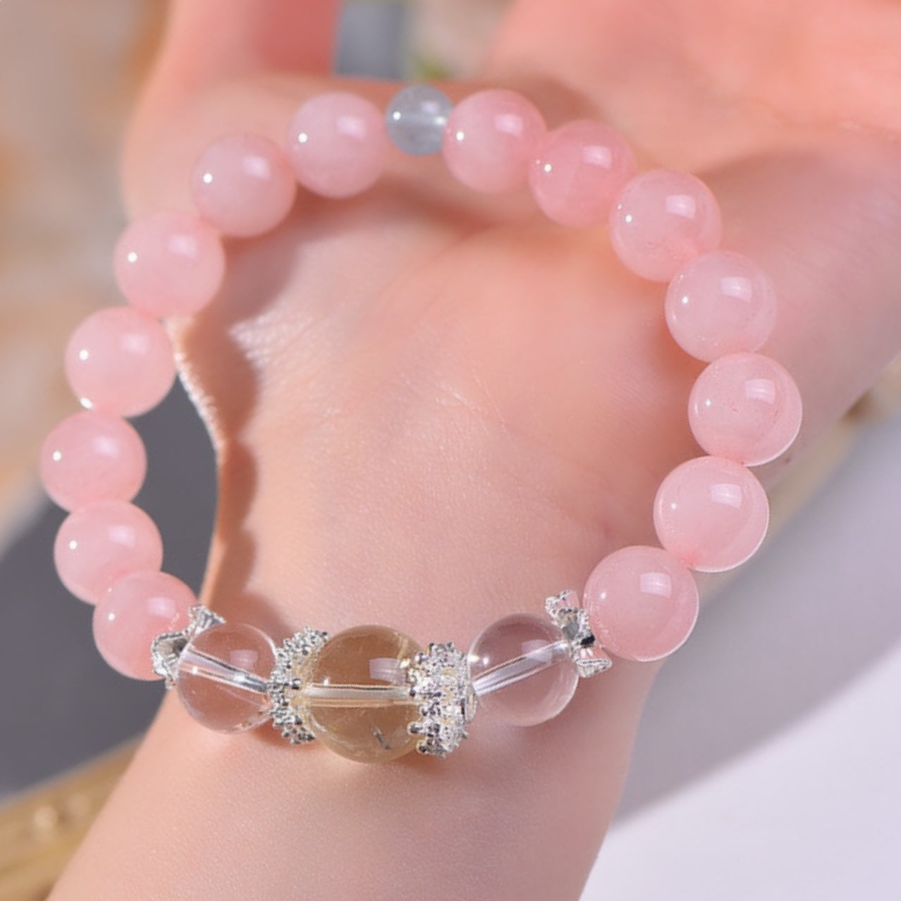 The bracelet is displayed flat, highlighting the dual effects of pink crystal in attracting love and yellow crystal in attracting wealth