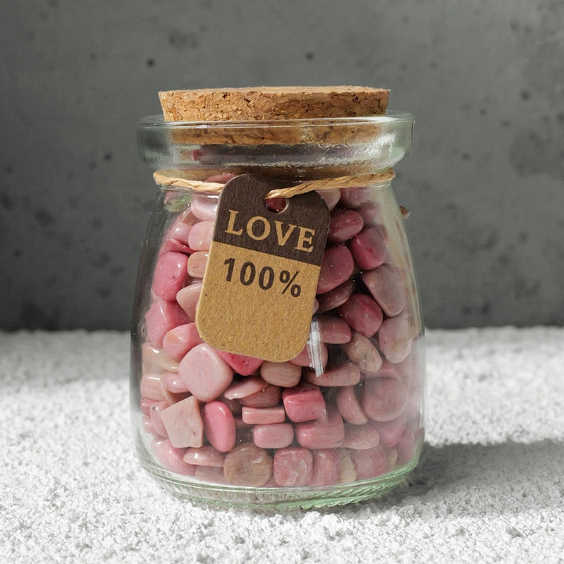 The "Star Wish Cabin" crystal intention bottle was held in the sunlight by a pair of hands, and the pink, purple and white crystals inside the bottle refracted brilliant light.