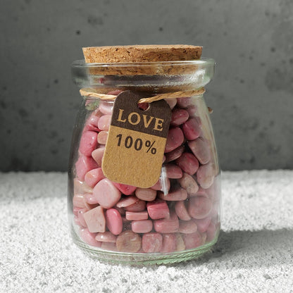 The "Star Wish Cabin" crystal intention bottle was held in the sunlight by a pair of hands, and the pink, purple and white crystals inside the bottle refracted brilliant light.