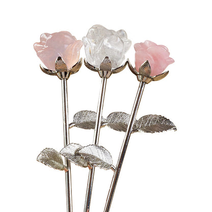 A crystal rose is placed on a simple dressing table, with scented candles and jewelry beside it, symbolizing a self-love ritual.