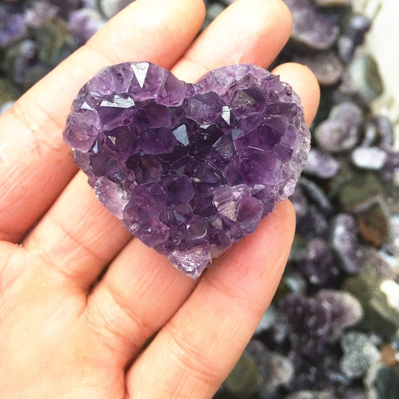 A close-up of the heart-shaped amethyst cluster on a white background showcases its perfect form