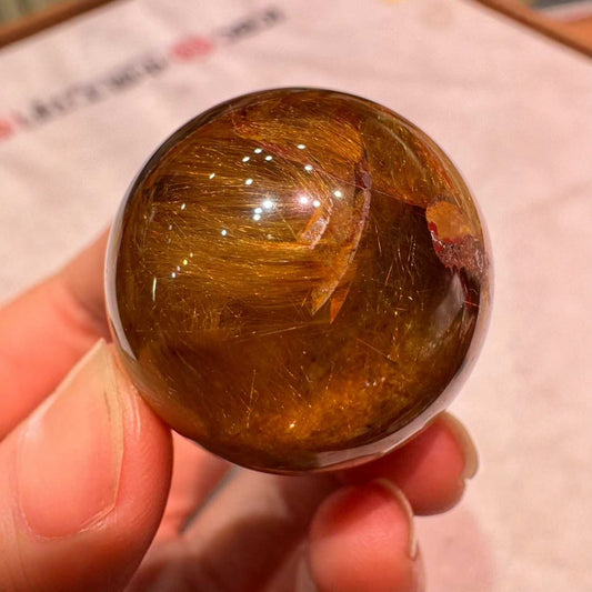 Golden rutilated quartz sphere with full rutile hair inclusions